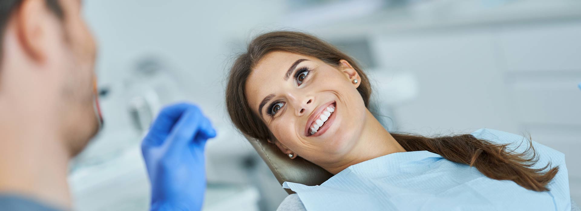 A woman is smiling happily after smile dental crowns.